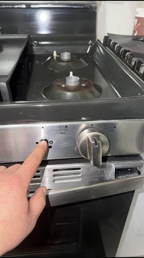 Technician performing diagnostic inspection on a gas range control panel in a New York City apartment