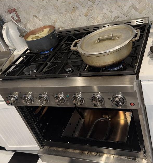 Professional six-burner gas range with marble backsplash in a luxury New York City kitchen